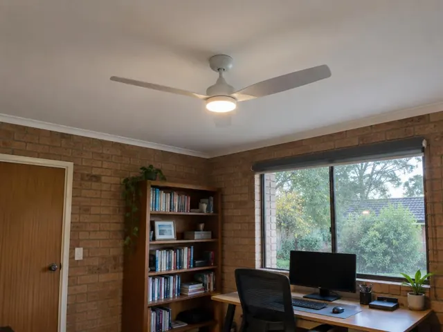Ceiling fan in a brick-walled home office with a window and desk in Wyoming