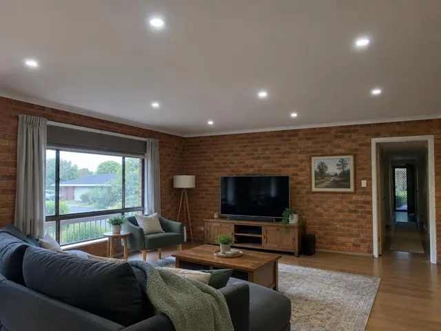 Living room with recessed LED downlights, brick feature wall, window and lounge room in Lisarow